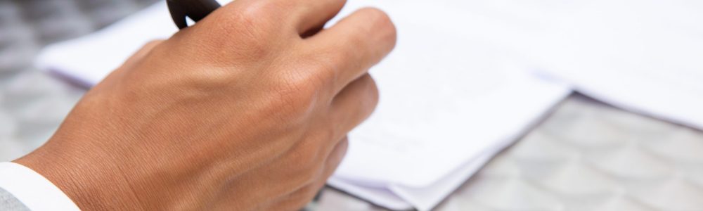 Closeup view of male hand holding pen. African American manager working with documents. Business concept